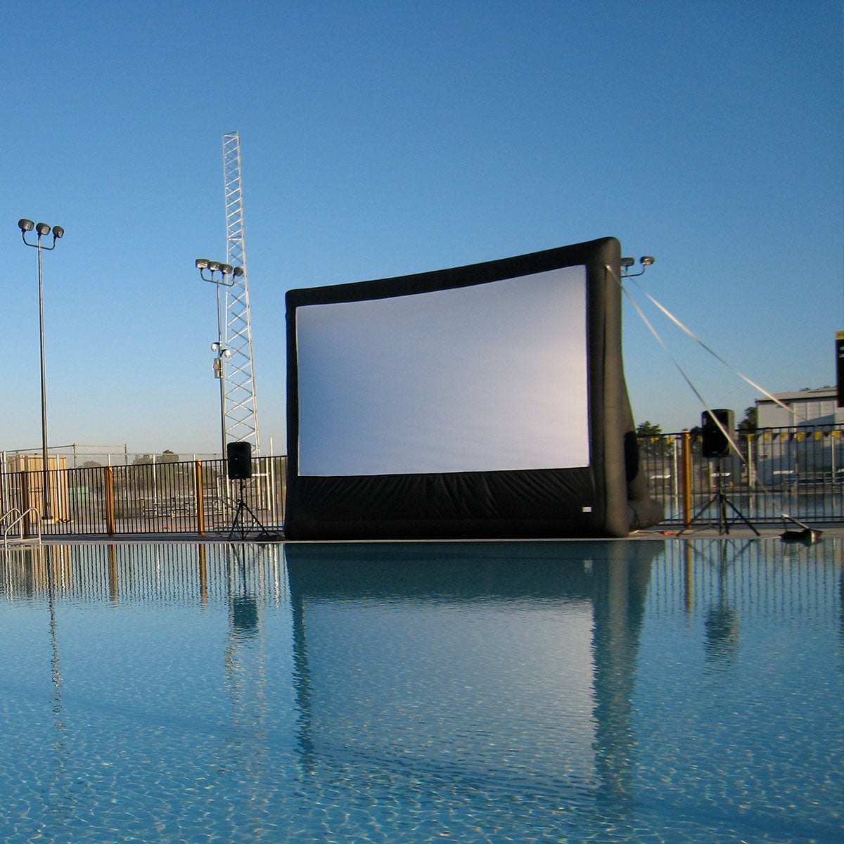 An Open Air Cinema Event Pro inflatable screen set up beside a pool, its white projection surface facing the camera